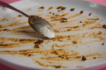 Fototapeta premium Empty Plate with Food Remnants and Spoon on Pink Background
