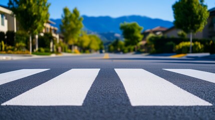 Obraz premium Suburban Street Crosswalk - A close-up view of a crosswalk on a quiet residential street, with houses and mountains in the background.