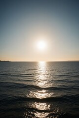 Obraz premium arafed view of the sun setting over the ocean with a boat in the distance