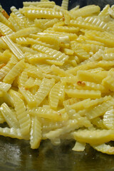 Deep frying French Fries in oil. Cooking potatoes. Fresh potato chips frying. Frying potatoes. Shallow depth of field.