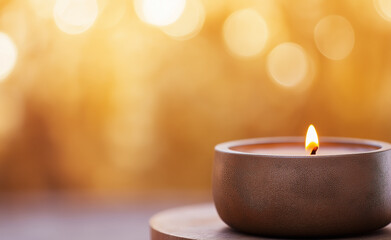 A lit tealight candle with a warm glow and blurred golden bokeh lights in the background.
