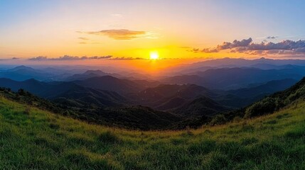 Fototapeta premium Sunset over mountain range, panoramic view, grassy foreground, peaceful sky. Use travel, nature