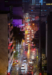 Evening traffic on a rainy street in Manila, Philippines with colorful city lights