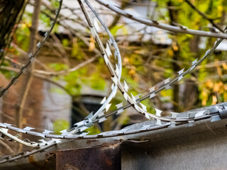 Close-up of barbed wire over a wall. The concept of imprisonment or restriction of territory in industrial production.