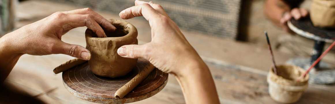 Naklejki A woman enjoys quality time as she shapes clay during their pottery class, banner