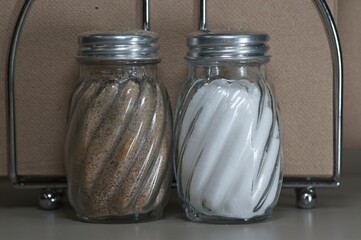 Glass salt and pepper shakers in front of a brown napkin
