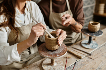 In a cozy pottery studio, a mature couple joyfully shapes clay together, sharing quality time.