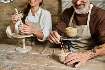 A beautiful couple enjoys quality time in a pottery class, shaping clay with love and laughter.