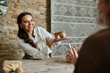 A mature couple enjoys shaping clay together in a pottery class, sharing smiles and love.