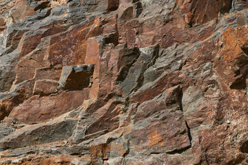 Rock fragment of dark gray rock with rusty iron hydroxide patina. Natural background. Copy space.