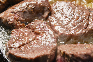 Searing beef meat roast  slices in cast iron skillet, shallow depth of  field.