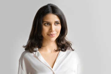 Fototapeta premium Smiling latin or eastern middle age female ceo leader businesswoman looking aside on grey background. Closeup headshot isolated face portrait of beautiful successful hispanic young business woman