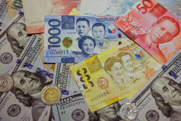 Various denominations of Philippine currency alongside American dollars and coins on a surface