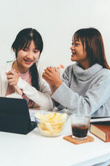 Female higher education student using laptop and studying book in home, Online learning.