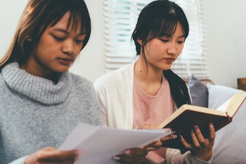Female higher education student using laptop and studying book in home, Online learning.