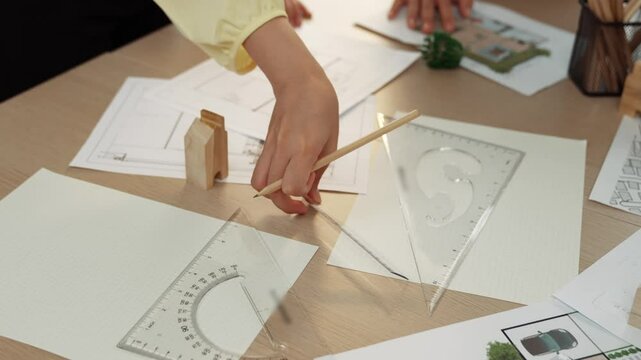 A video of architect use measurement tools and pencil to measure blueprint. Architect design house construction on a table at studio, with architectural plan scattered around. Focus hand. Delineation.