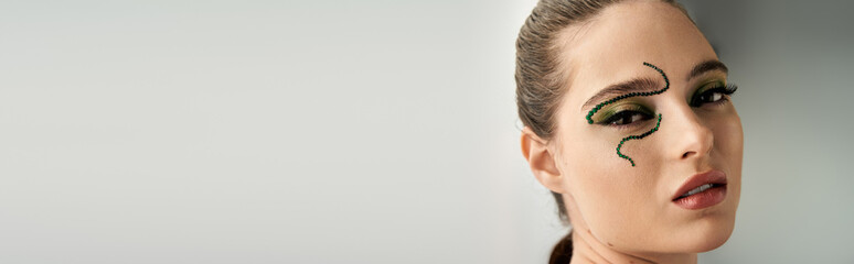 A young woman showcases transformative snake makeup in a captivating studio setting, banner