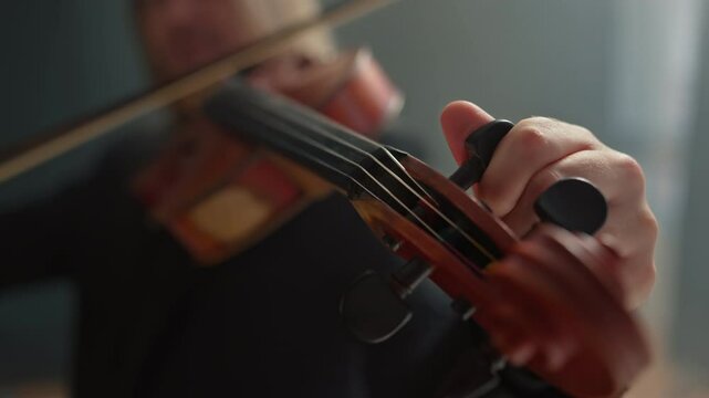 A musician turns the tuning pegs to tune the strings of a violin to the desired sound. The violinist listens carefully to the sound. Tuning a musical instrument.