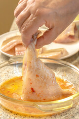 Chef dips a piece of fish into liaison - a mixture of raw eggs, salt, paprika before frying
