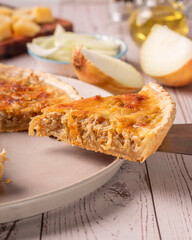 quiche de cebola caramelizada com elementos ao redor como azeite, queijo parmesão e cebola fatiada 