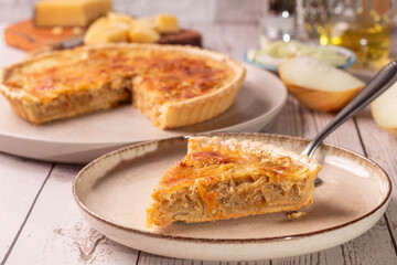 quiche de cebola caramelizada com elementos ao redor como azeite, queijo parmesão e cebola fatiada 