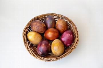 Obraz premium Decorative Easter eggs in a basket placed on a plain white surface