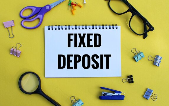 Fixed deposit investment concept on open notebook with different stationery.