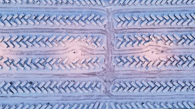 Lights illuminate central area of massive car scrap yard covered in snow, aerial