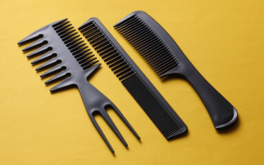 Set of black plastic combs on yellow background