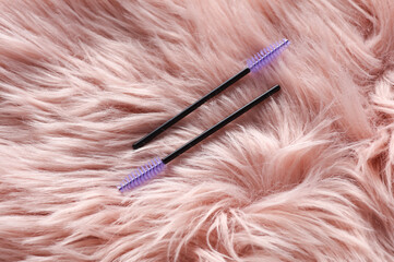Naklejka premium Eyelash brushes on pink fur background