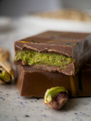 A piece of Dubai chocolate with pistachio paste and kunefe filled milk on a white background. Popular food concept. Vertical orientation. Macro photography