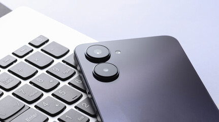 Modern smartphone with dual camera and laptop on white background