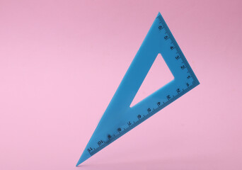 Ruler triangle floating on pink background.