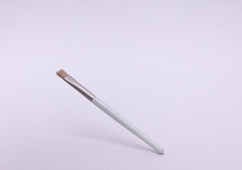 Gray makeup brush floating on white background