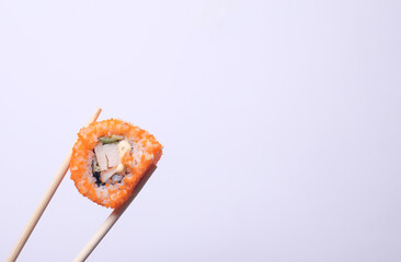 Chinese chopsticks holding sushi roll on white background