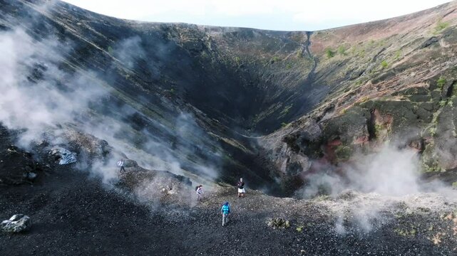 Fast backward drone shot reveals panoramic view of Par&iacute;cutin Volcano with hikers atop the crater and volcanic steam rising