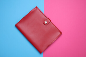 Red leather notebook or document organizer on blue pink background