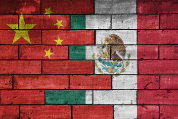colourful painted big flag of china and flag of mexico on a massive old brick wall background....