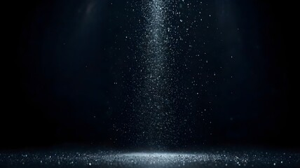 Light mist sprayed across a dark background with visible droplets glistening under bright lighting.

