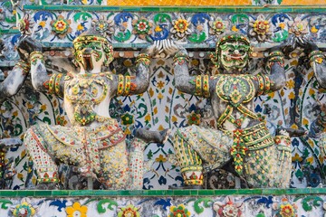 Obraz premium Spectacular temple sculptures at Wat Arun in Thailand showcasing intricate details and traditional artistry near the riverside