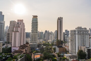 Obraz premium City skyline of Bangkok showing modern skyscrapers and the sun setting over the urban landscape