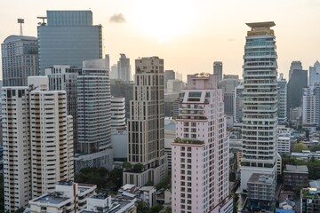 Obraz premium Cityscape of modern Bangkok at sunset showcasing towering skyscrapers and urban architecture