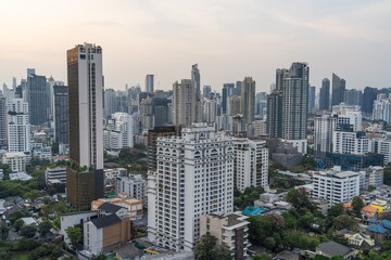 Obraz premium City skyline of Bangkok featuring modern buildings and lush greenery during sunset