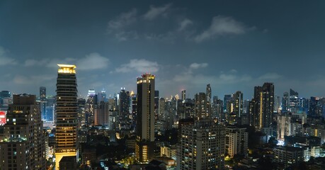 Vibrant city skyline of Bangkok illuminated by night as clouds drift above urban landscape and...