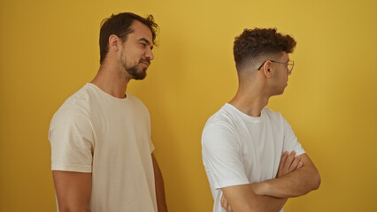 Father and son standing against a yellow wall, embracing the essence of family and love in a simple isolated background.