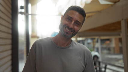 Obraz premium Young man in urban setting smiling on a city street showcasing a vibrant and welcoming atmosphere in a bustling town environment during daytime.