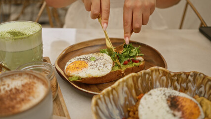 Woman enjoying a fresh breakfast of avocado toast with a fried egg and matcha latte at a cozy restaurant table