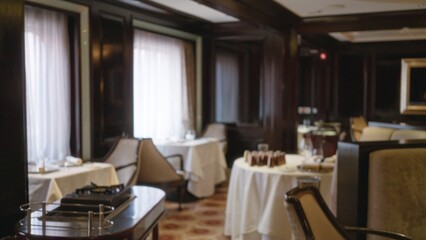 Blurred luxury restaurant interior with elegant decor and table settings, featuring warm lighting and plush seating for an upscale dining experience.