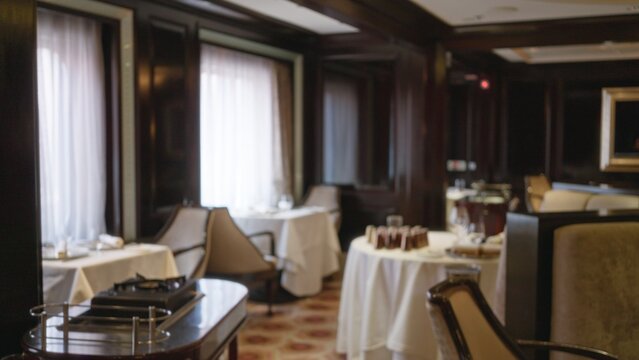 Blurred luxury restaurant interior with elegant decor and table settings, featuring warm lighting and plush seating for an upscale dining experience.