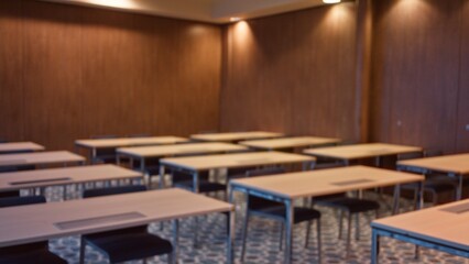 Empty classroom with several desks and chairs arranged in rows, captured in a soft focus, creating a serene and quiet indoor educational environment.